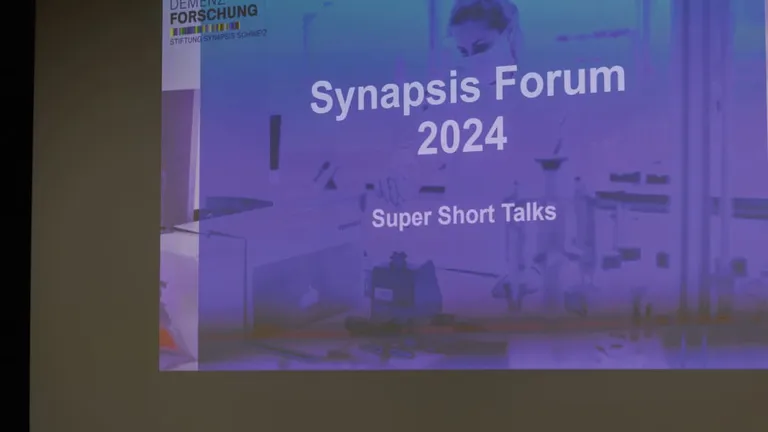 Powerpoint presentation with title of Synapsis Forum slide projected onto the wall.